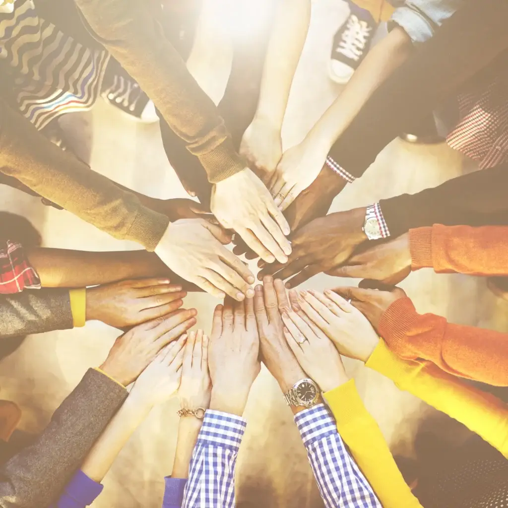Diverse hands coming together in a supportive circle, symbolizing community and connection in an Intensive Outpatient Program for mental health and substance use recovery.