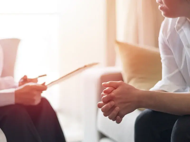 Client engaged in therapy session with counselor, discussing behavioral health and recovery strategies in a comfortable setting.