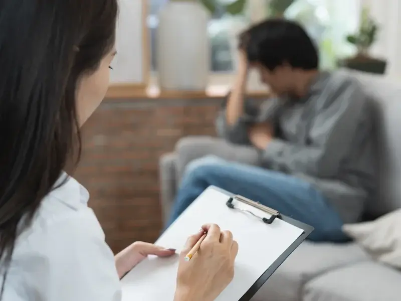 Therapist taking notes while conducting a substance use screening session with a client in a supportive environment, emphasizing accountability and recovery at SagePoint Behavioral Health.